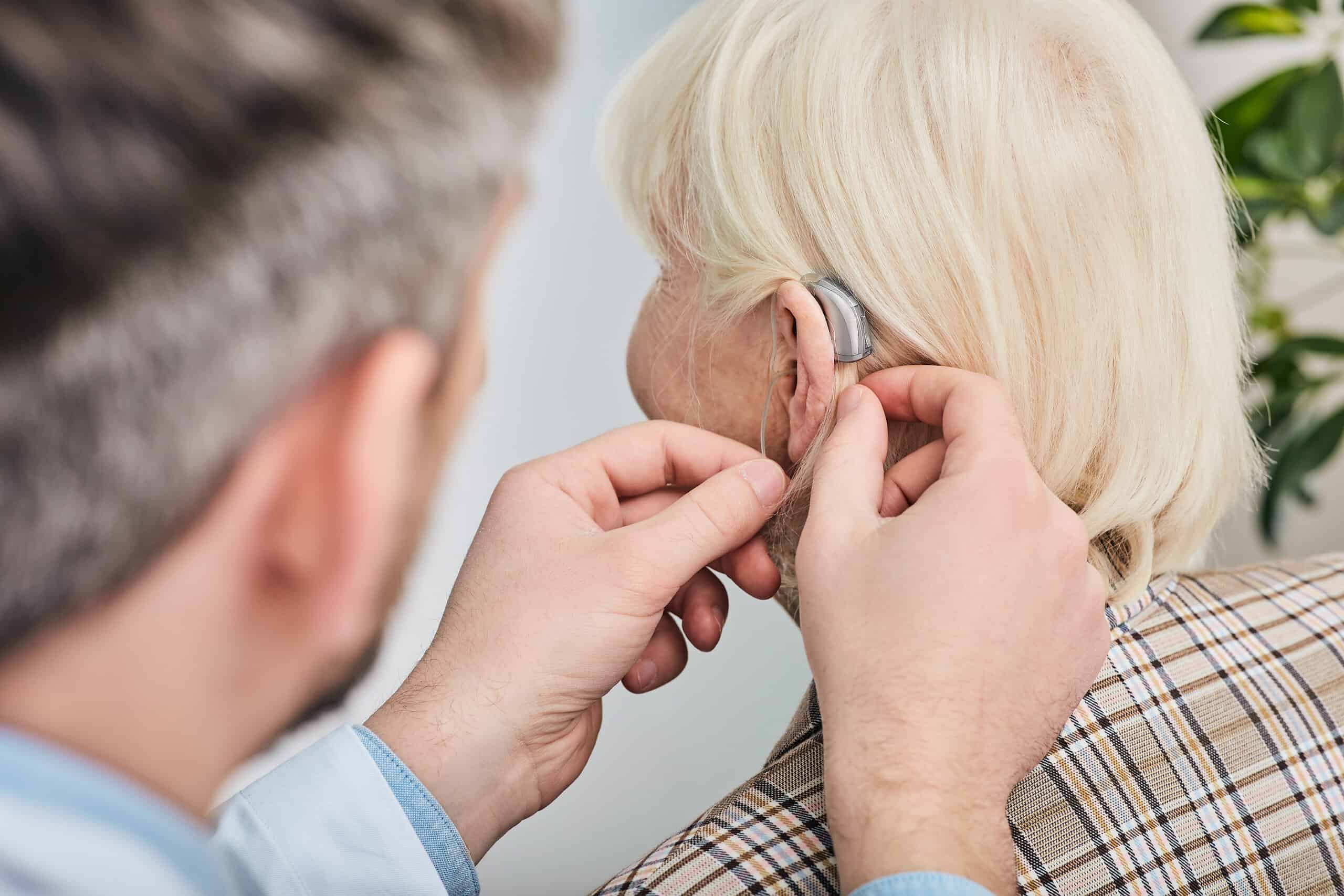 Audiologist Inserting Hearing Aid On A Senior Woman